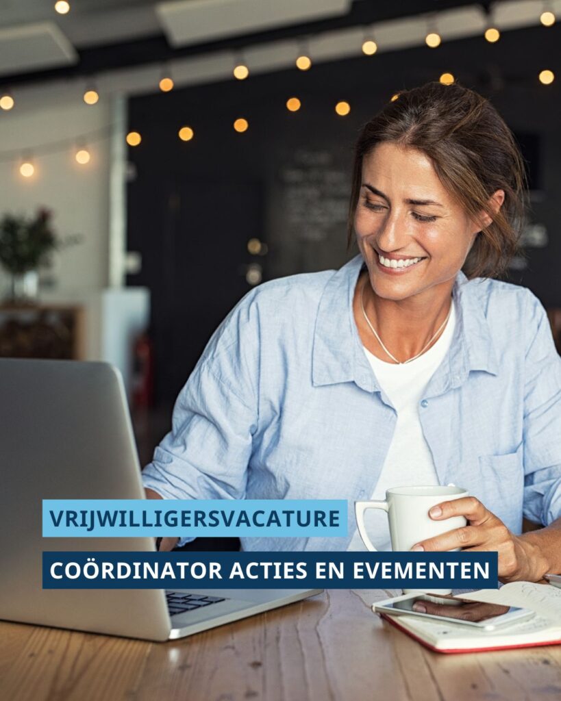 Vrouw zit lachend aan bureau. Met één hand werkt ze op haar laptop en met de andere hand houd ze een mok vast. Op de foto staat de tekst ‘Vrijwilligersvacature’ en ‘Coördinator Acties en Evenementen’