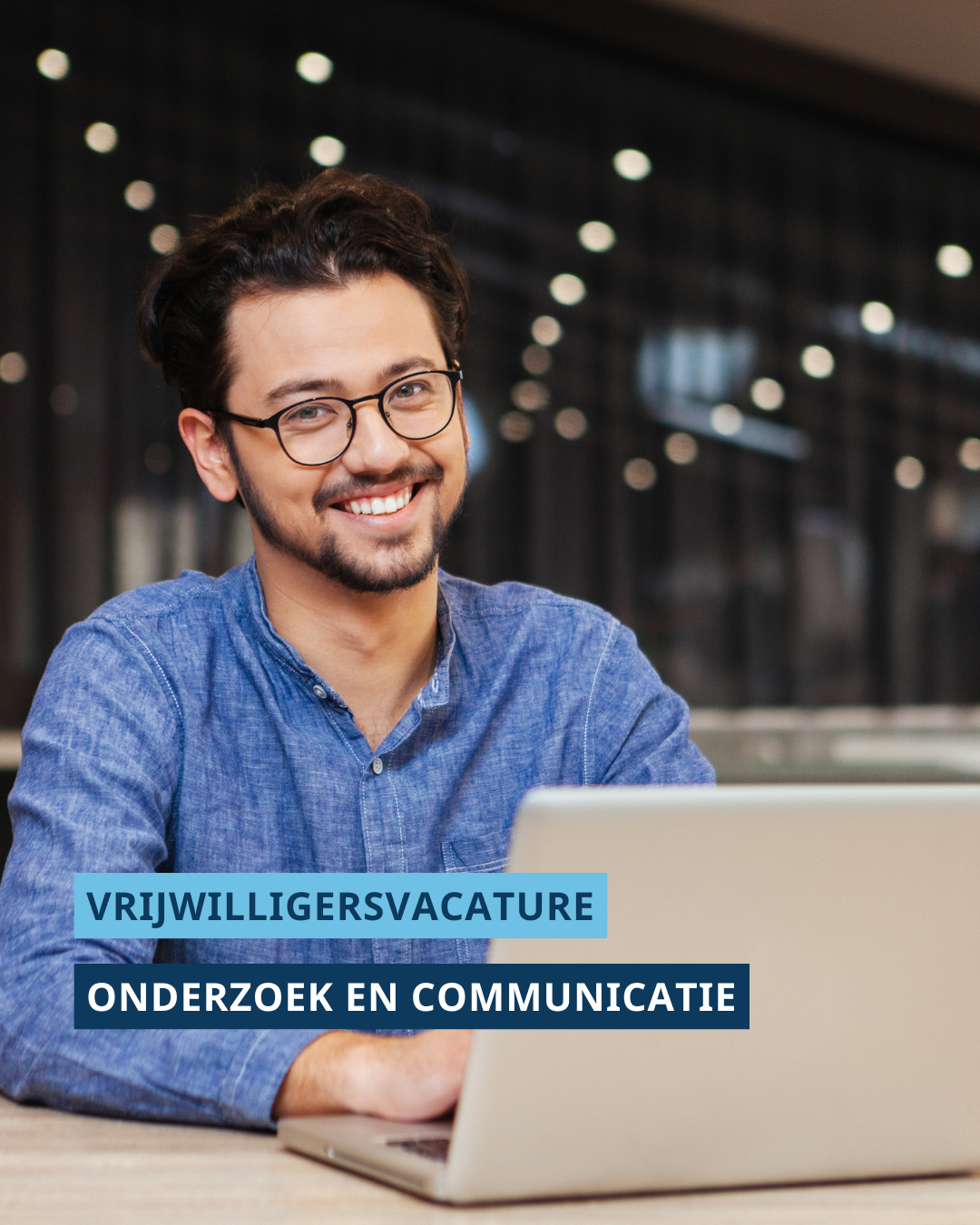 man lachend achter laptop. Onderaan de foto staat de tekst: vrijwilligersvacature. Onderzoek en communicatie