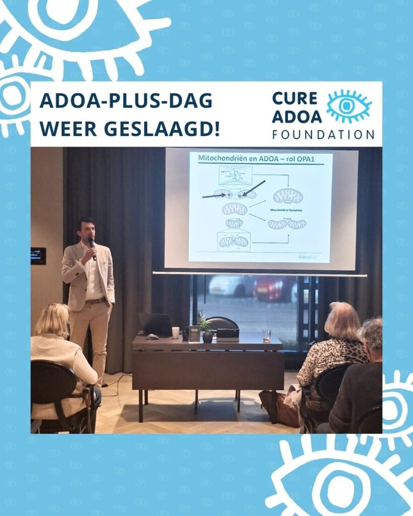 Dr. Jeroen Smits spreekt een zaal toe met naast hem een presentatie met daarop een afbeelding met mitochondriën. Boven de foto staat de tekst ‘ADOA-plus-dag weer geslaagd!’