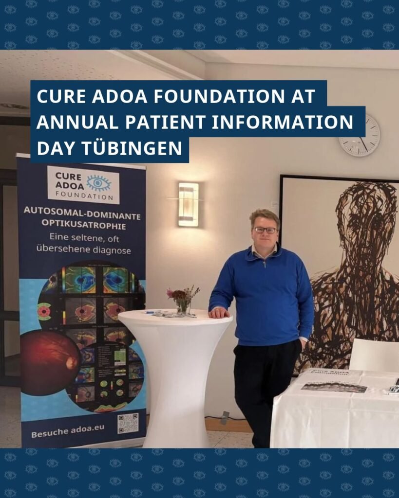Foto van Felix met de ADOA-stand in Tübingen. Bovenin de foto staat de tekst 'Cure ADOA Foundation at annual patient information day in Tübingen'.